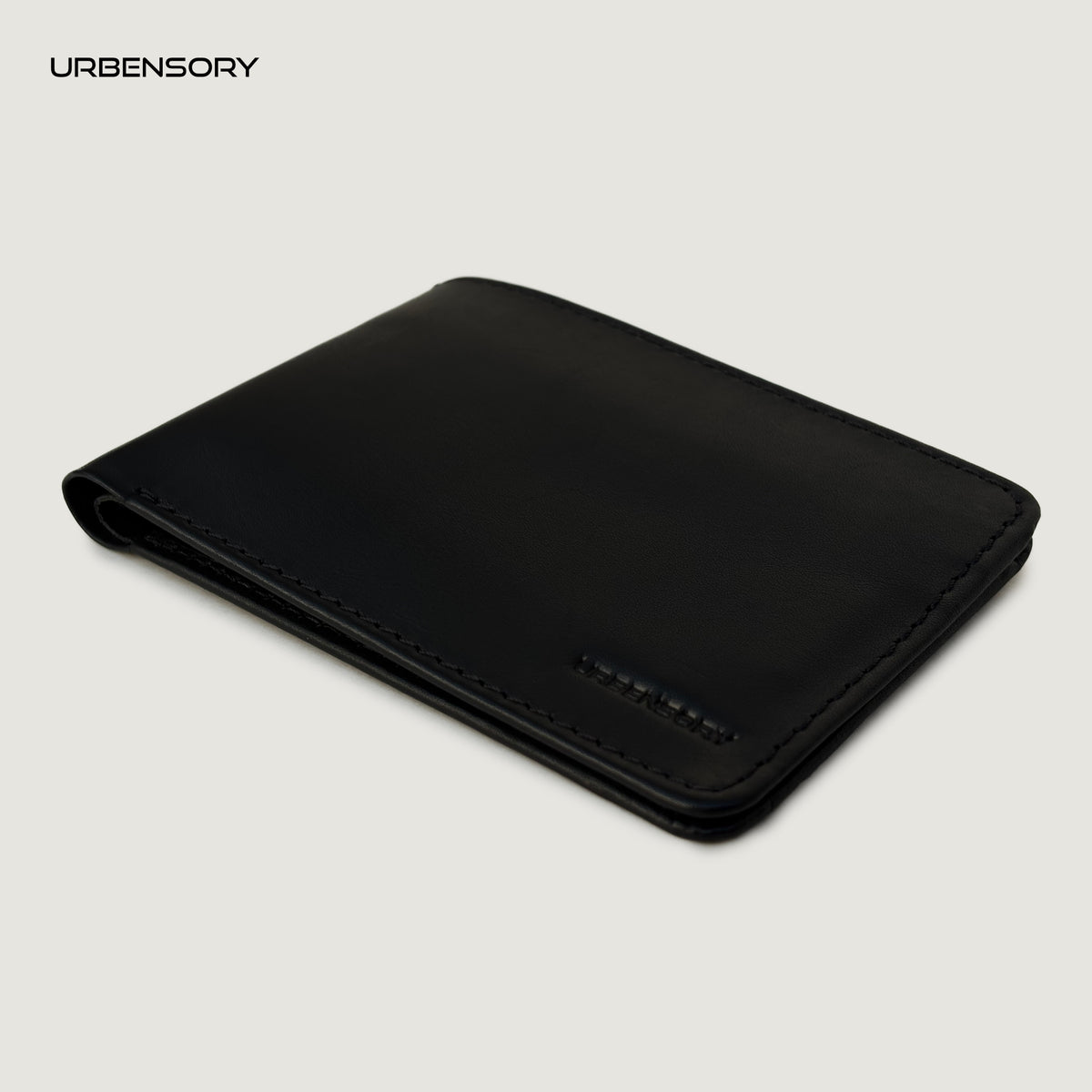 The Zero black leather bifold wallet by URBENSORY, shown closed at a three-quarter angle with stitched edges and an embossed logo.